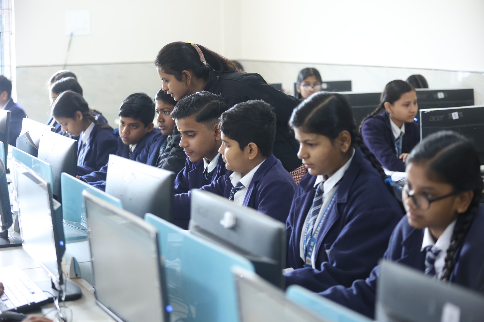 Teacher leaning over a student to help in the computer lab