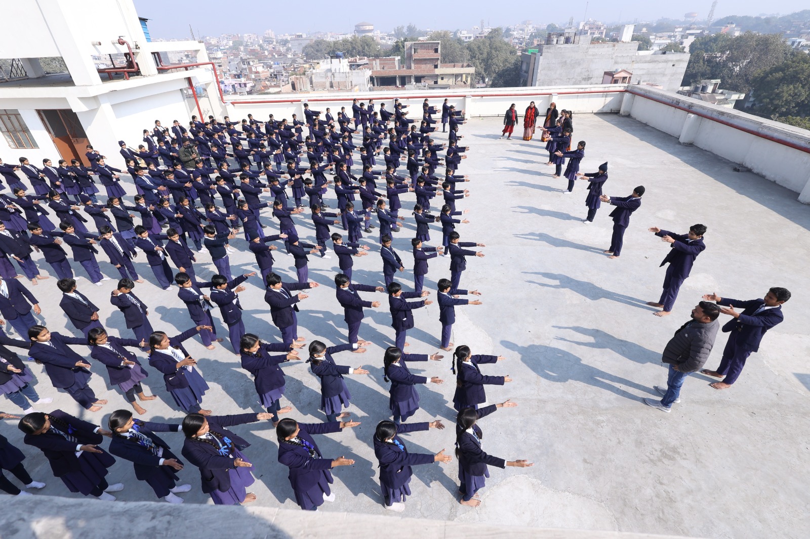 Wide rooftop view of students performing yoga with arms extended outward