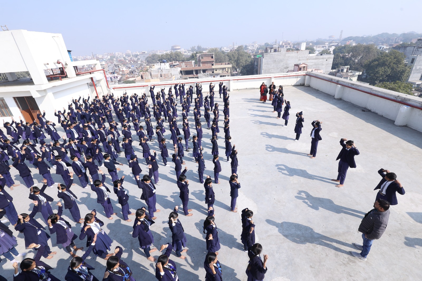Rooftop view of students with arms raised in sun salutation